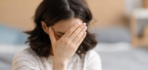 Sad tired young woman is touching her forehead, while having headache, migraine or depression.